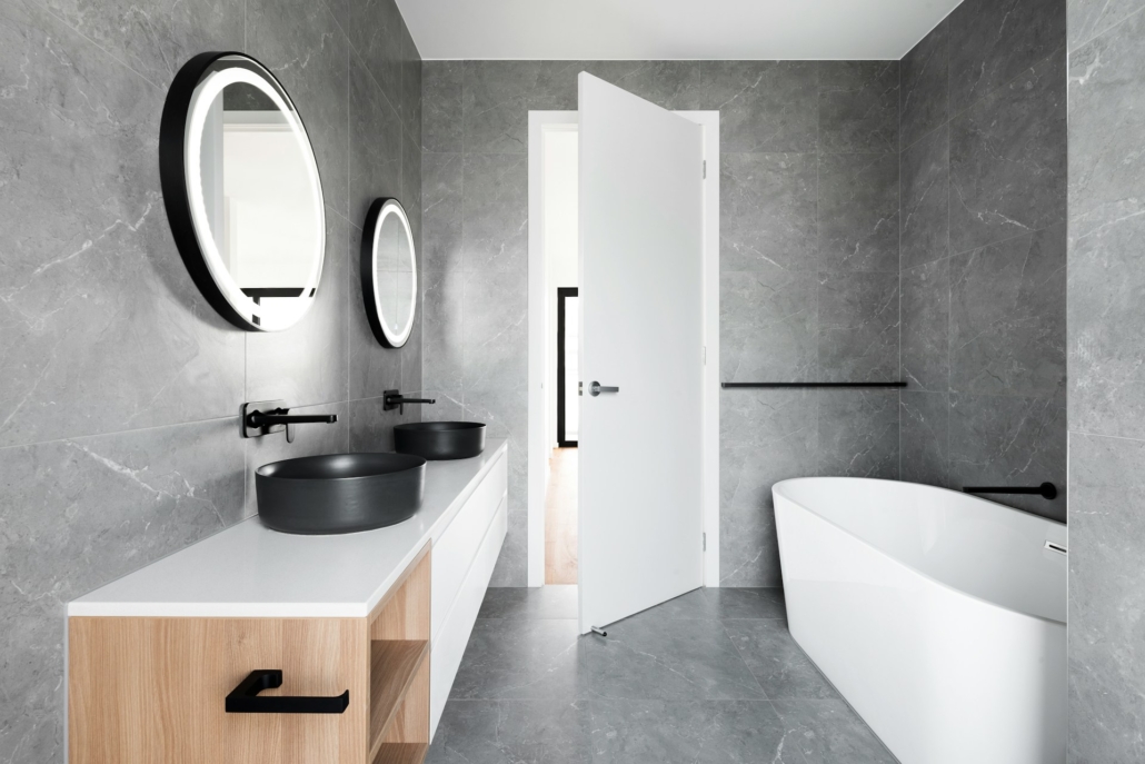 een grijze badkamer met een wit bad en een meubel van hout