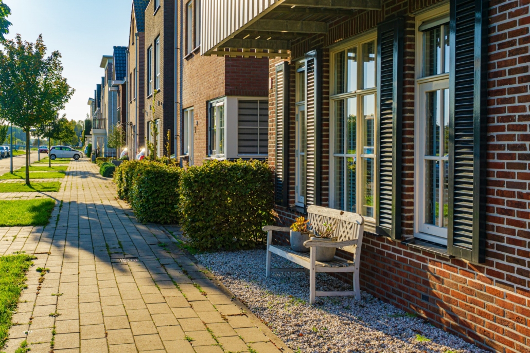 Een rij moderne Nederlandse huizen met goed onderhouden voortuinen, waarbij spouwmuurisolatie zorgt voor energie-efficiëntie en comfortabele binnentemperaturen.