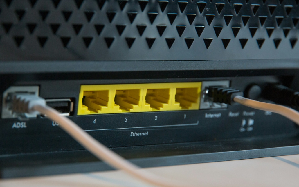 Achterkant van een internetrouter met gele Ethernet-poorten en aangesloten kabels. Duidelijk zichtbaar zijn de ADSL-, USB- en Ethernet-verbindingen voor netwerkconnectiviteit