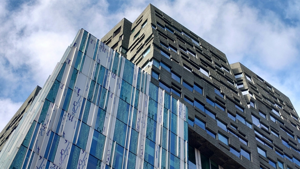 Modern hoog gebouw met glas en steen, een voorbeeld van een potentiële vastgoedbelegging in stedelijke architectuur.