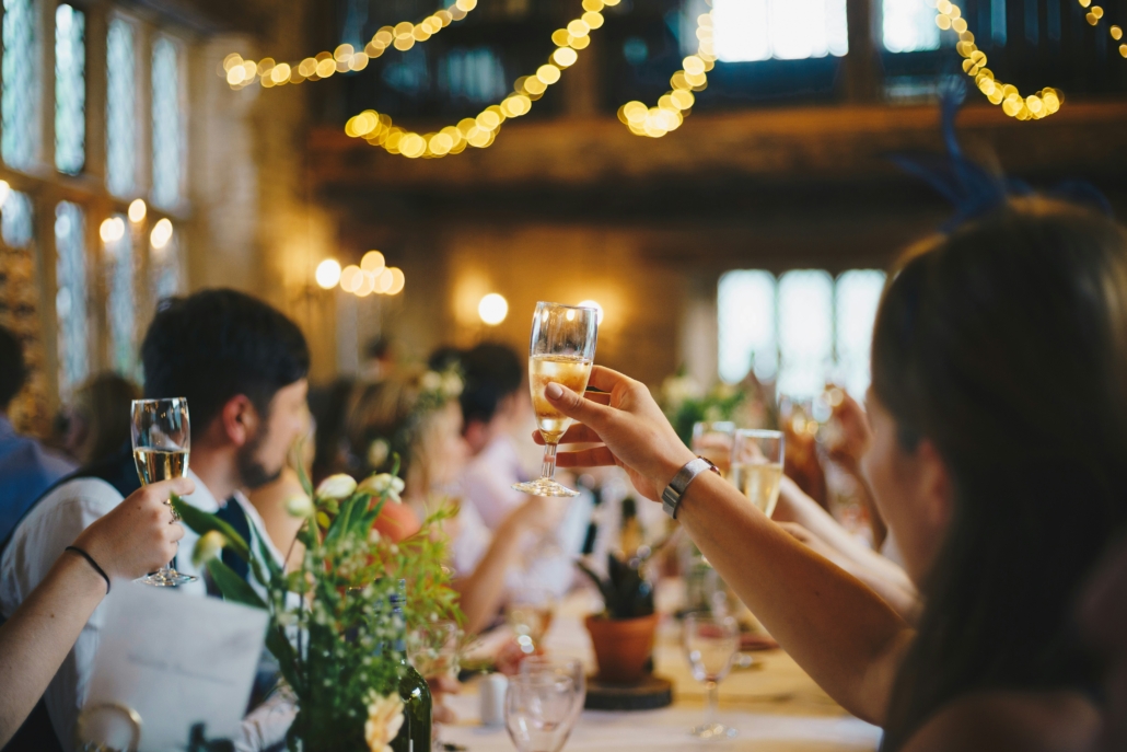 Feestelijke sfeer tijdens een huisfeest met gasten die proosten met champagneglazen, sfeerverlichting en een ontspannen ambiance, ondersteund door een geluidsversterker voor muziek en gezelligheid.